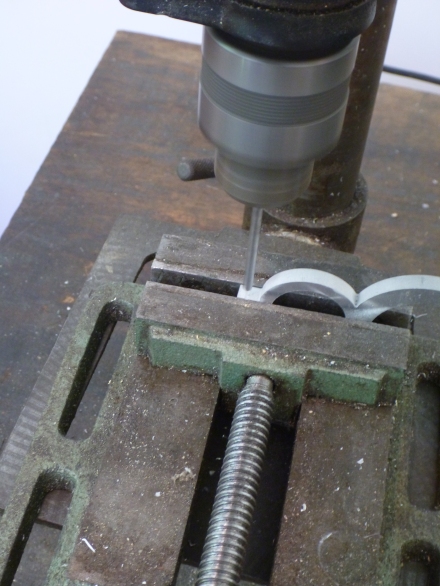 Drilling a bolt hole in the cut edge of the clamp with a drill press. The indentation in the cut line helps locate the correct spot for the hole.